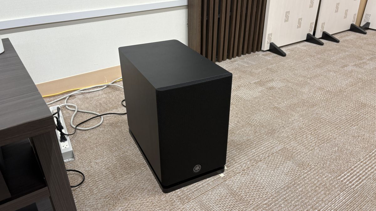 Yamaha True X Surround 90A system (soundbar, surround speakers and subwoofer) in a plain testing room with a TV.