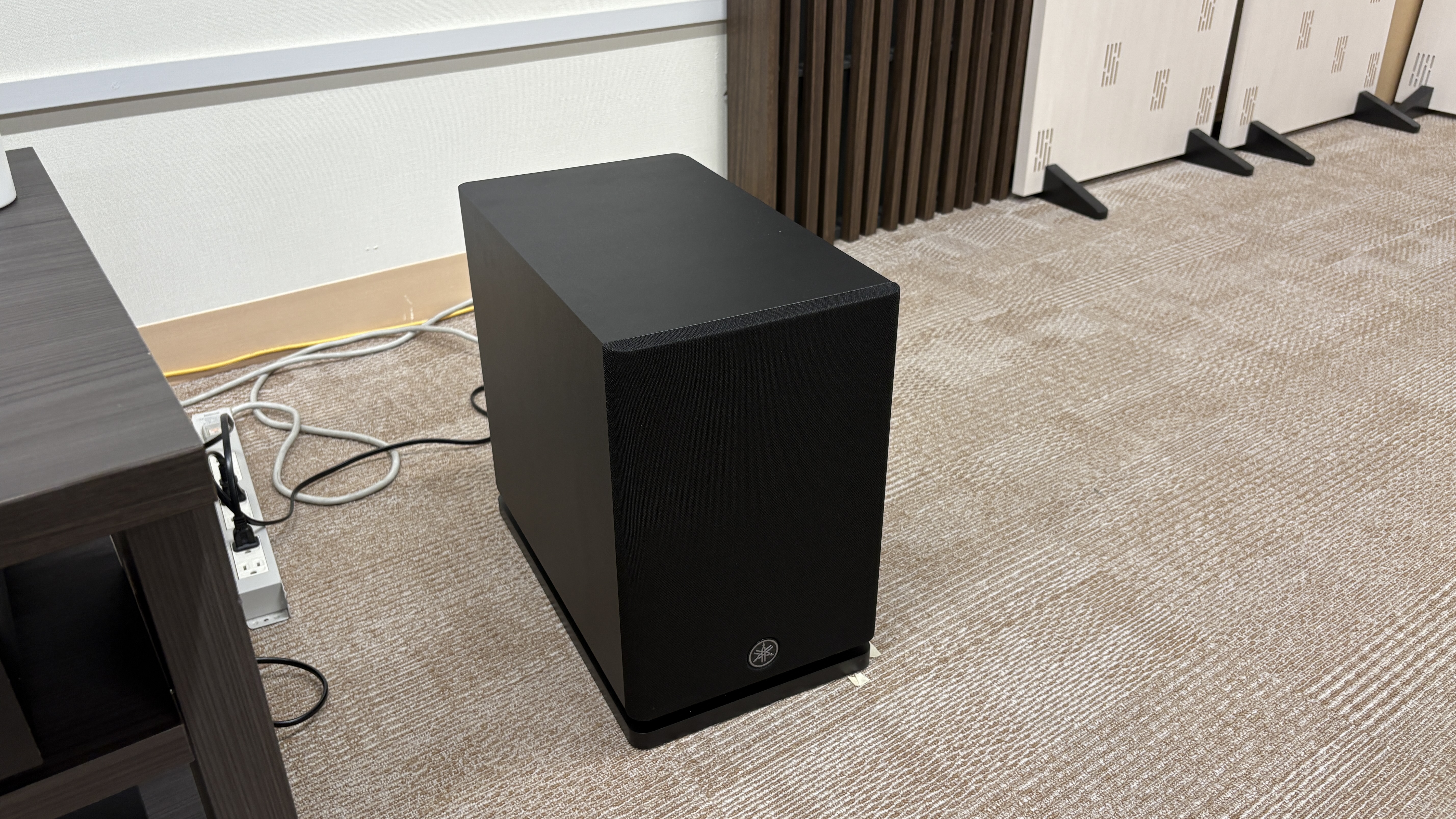Yamaha True X Surround 90A system (soundbar, surround speakers and subwoofer) in a plain testing room with a TV.