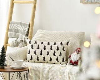 living room with a ladder display and christmas tree and a white couch with christmas pillows on it
