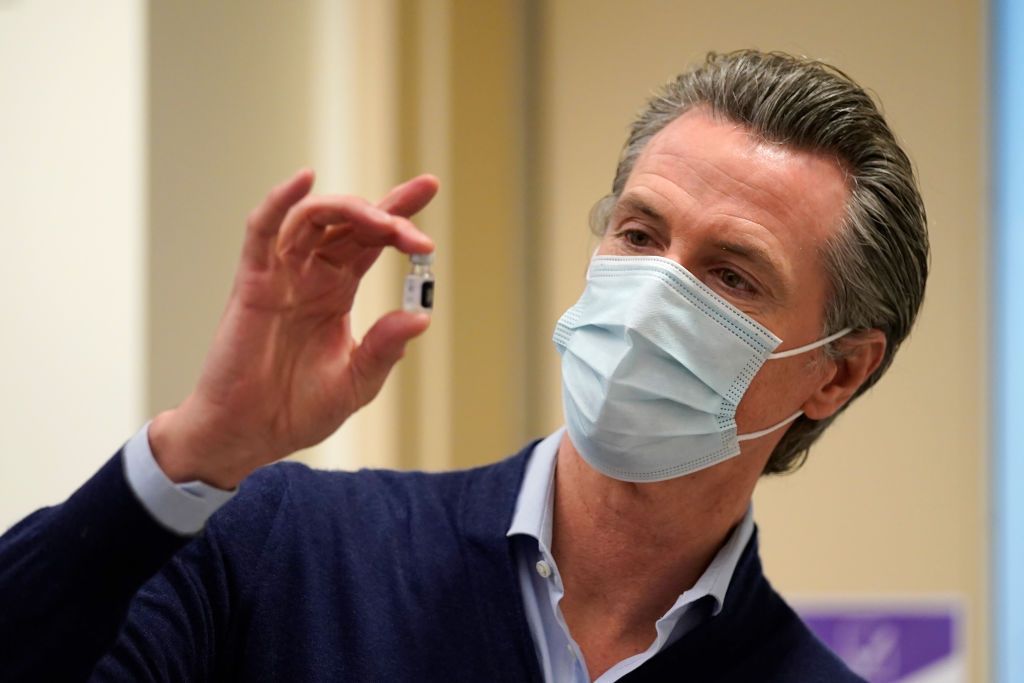 California Gov. Gavin Newsom looks at a COVID-19 vaccine.