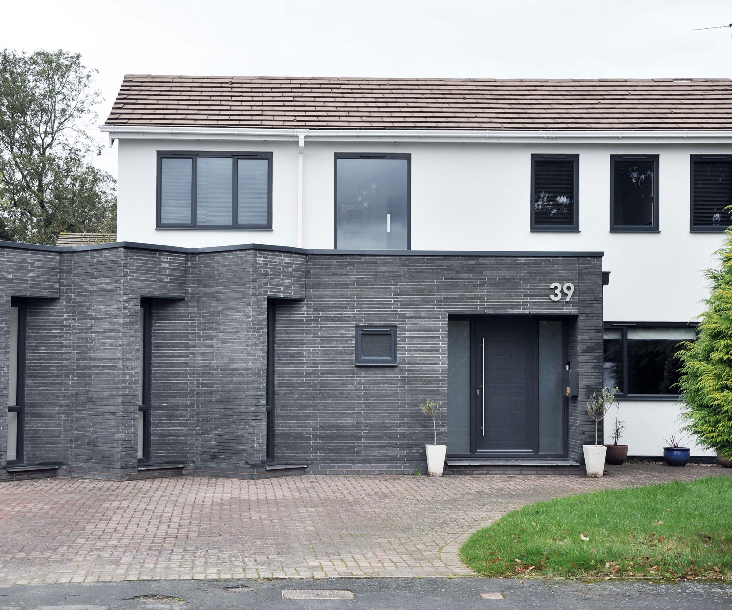 modern white house with dark grey brick front extension