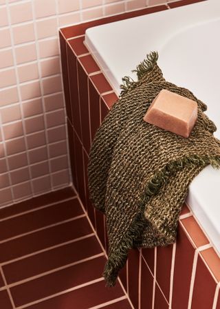 a red and pink bathroom with a bathtub with soap and cloth