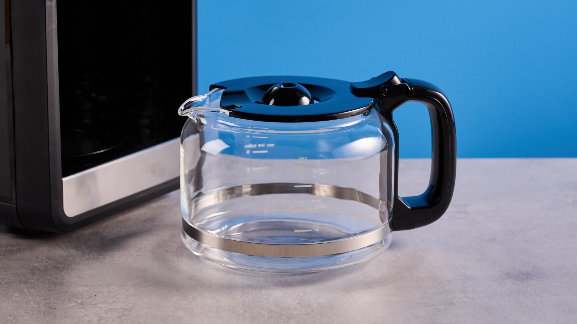 the gevi 10-cup drip coffee maker with grinder photographed against a blue background, showing the glass carafe, water tank, touch screen, and accessories including plastic filter