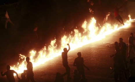 Protesters run near a line of fire during demonstrations in Cairo Sunday