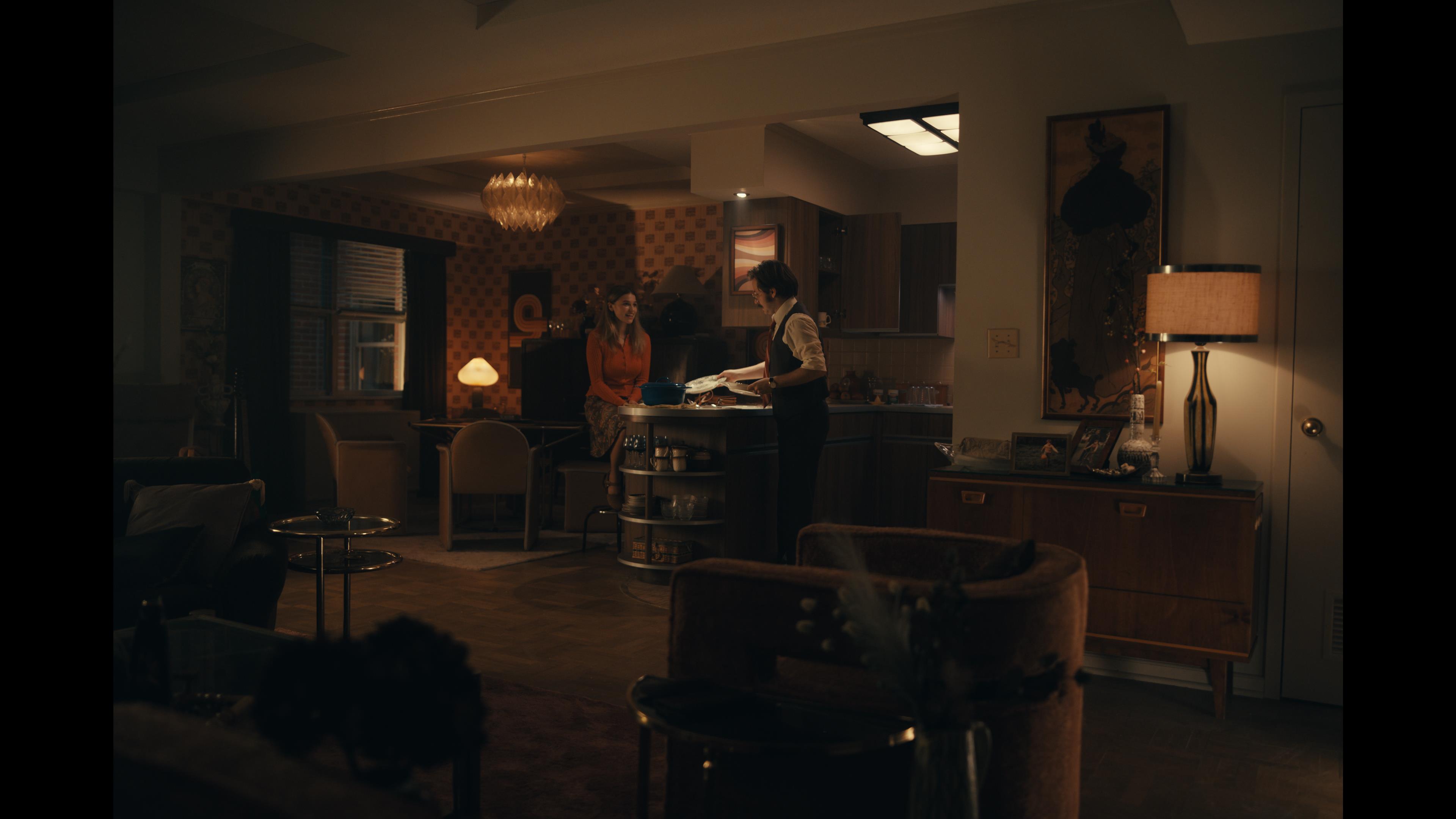 A series of film stills and photographs from a 1970s-inspired set featuring vibrantly decorated interiors with layered furniture and warm lighting, along with characters dressed in vintage clothing whether indoors or at parks, in cards, or at markets outdoors.