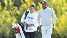Tiger Woods and his caddie Lance Bennett look on during the first round of the Genesis Invitational