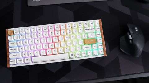 A Keychron K2 HE gaming keyboard with a wood finish and white keycaps with RGB enabled.