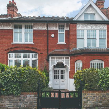 Red brick house with a front gate and a hedge