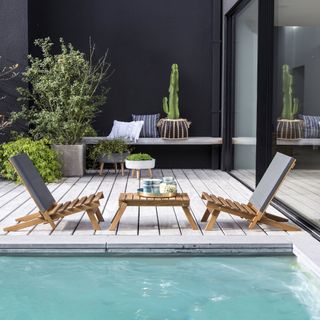 pair of low lounger chairs next to a swimming pool