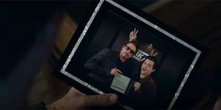 Tony Stark holding a photo of himself and Peter Parker