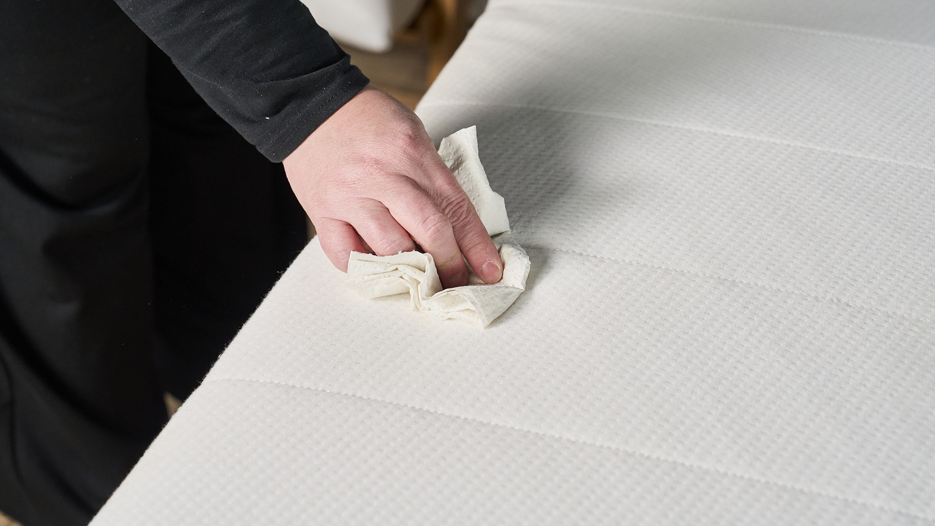 A woman blotting a mattress with a paper towel