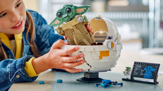 A child playing with the Lego Grogu with Hover Pram set