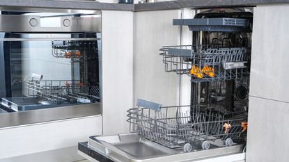Once you know how to get rid of a smell in the dishwasher, yours will be gleaming too like this open dishwasher in a neutral colored kitchen with an oven beside it