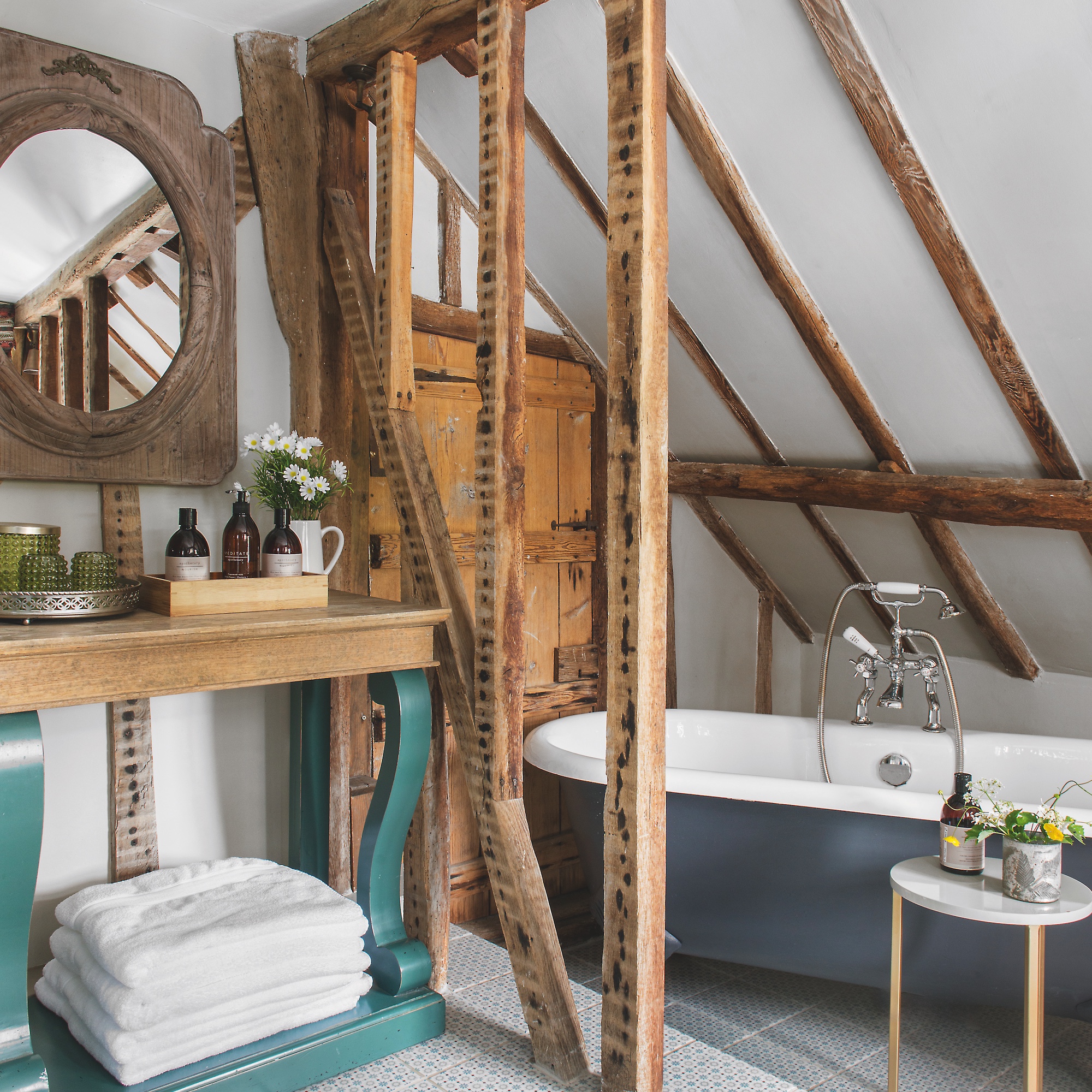 bathroom in eaves with exposed beams and rolltop bath