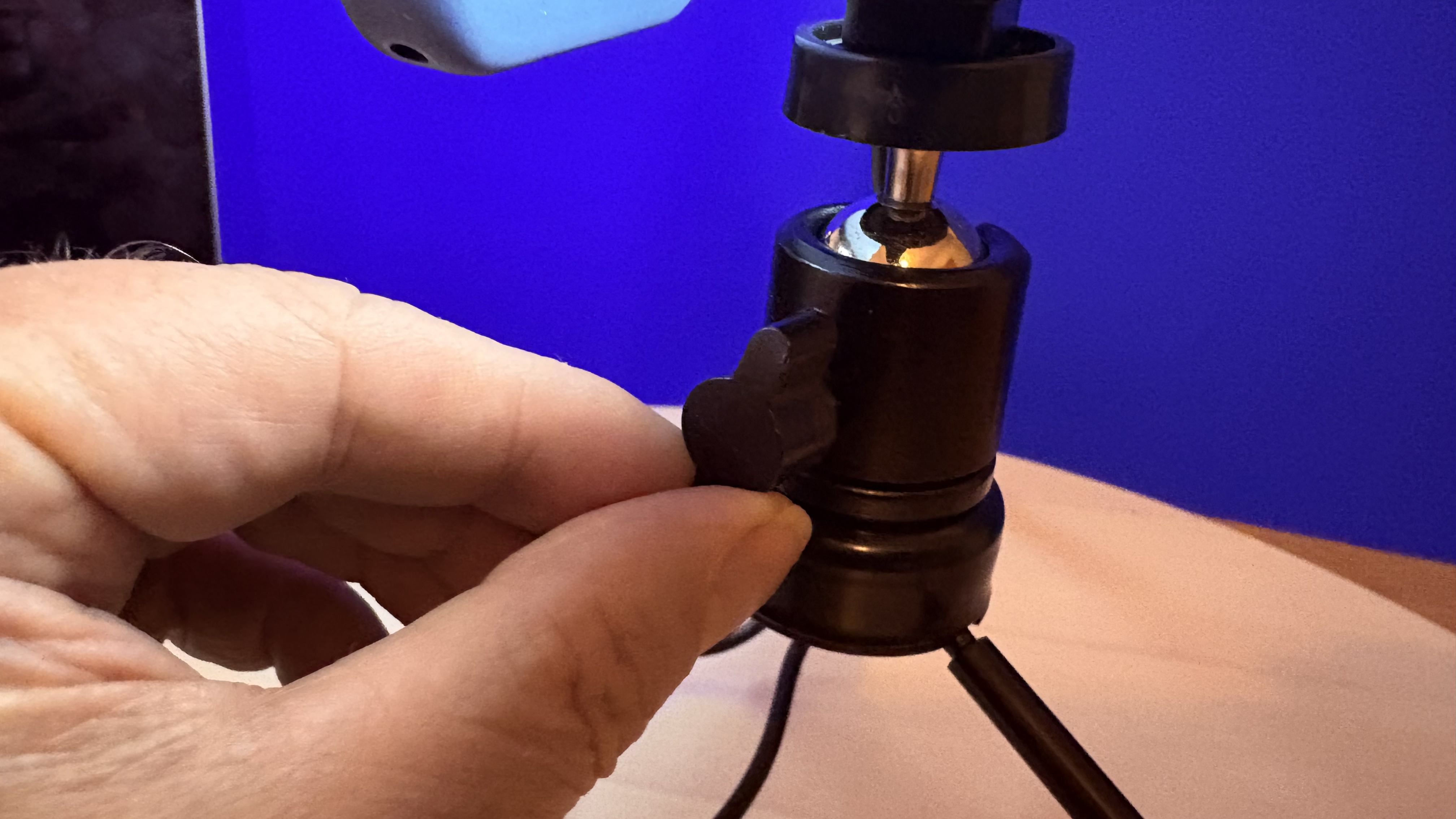Close-up of the tripod&amp;rsquo;s ball-head, with a hand adjusting the handle that tightens or loosens the angle of tilt.