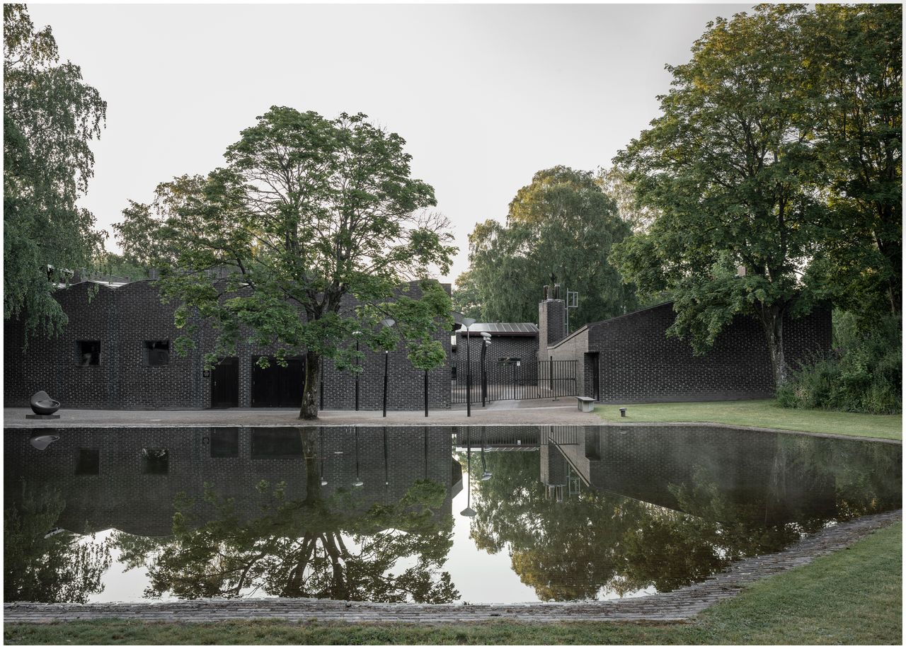 Exterior of dark brick church next to body of water