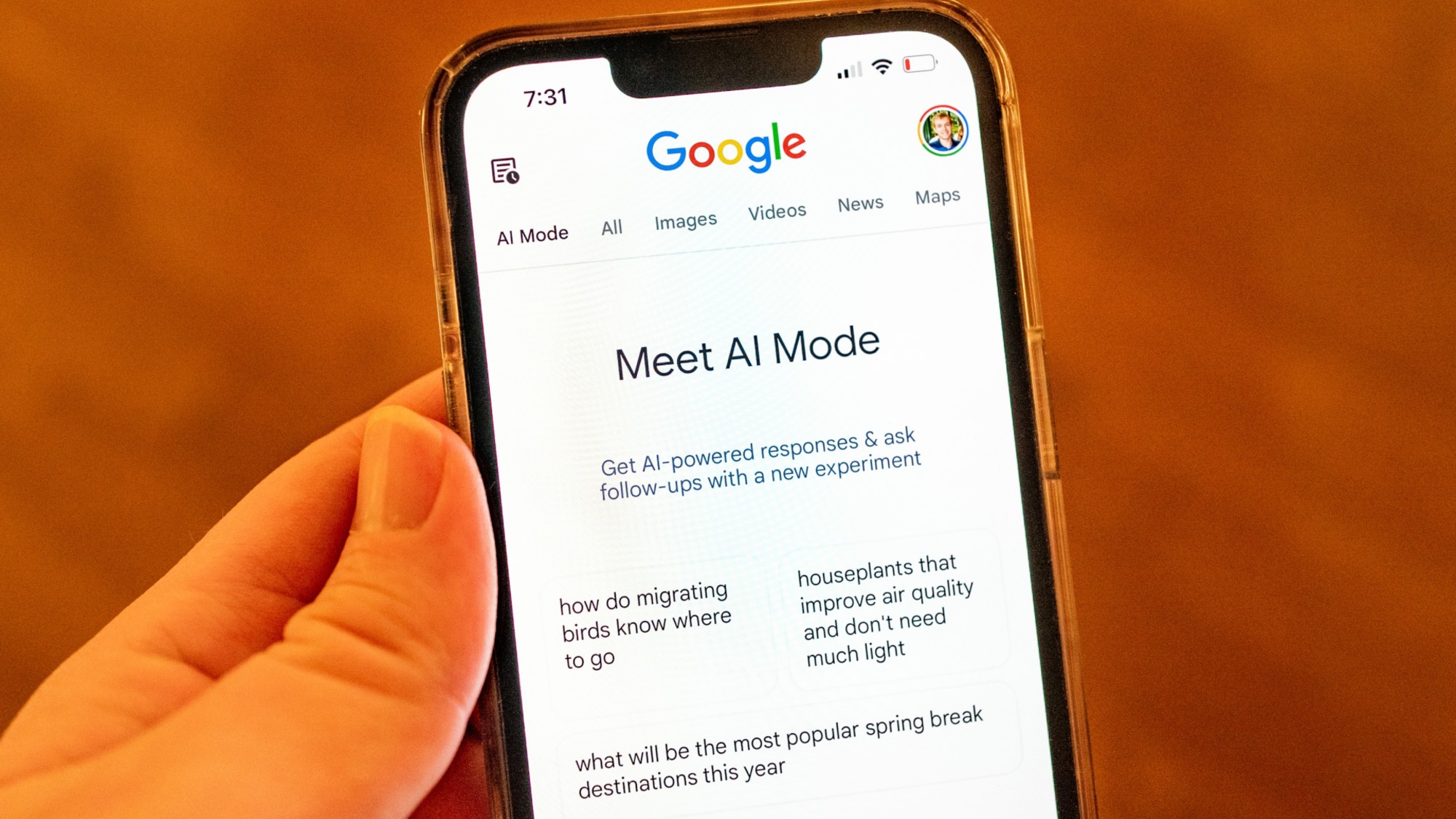 Close-up of a person's hand holding an iPhone and using Google AI Mode