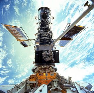 NASA astronauts John Grunsfeld and Steven Smith work to upgrade the Hubble Space Telescope during the STS-103 servicing mission to the observatory in December 1999. NASA has flown five servicing missions to repair and upgrade Hubble during its 25-year history.