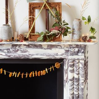 Dried orange slices on garland hanging from marble mantelpiece