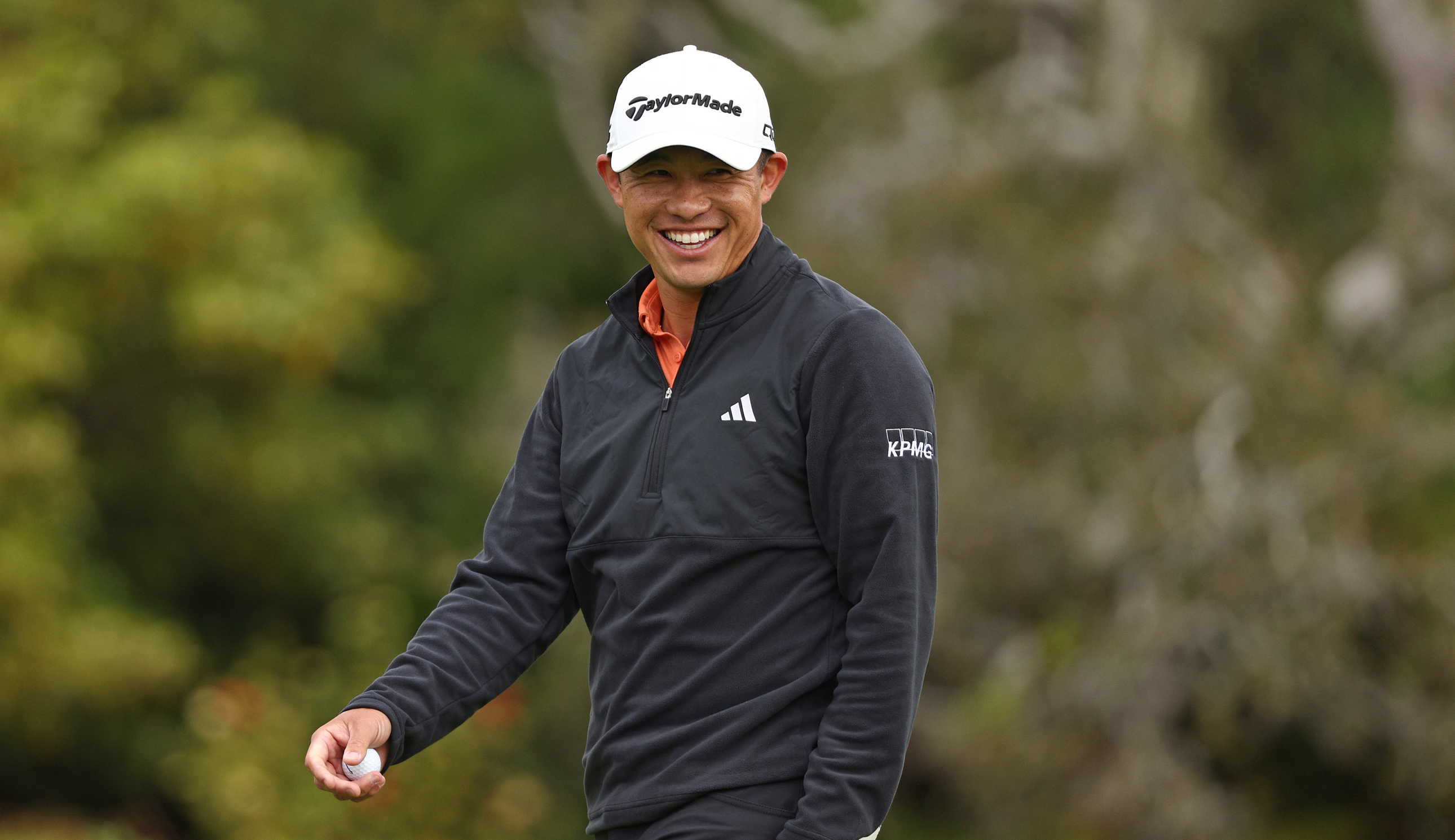 Collin Morikawa smiles walking off the green