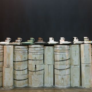 Dinner plates, cups and mugs on a wall made of ceramic cylinder blocks