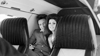 Elvis Presley peeks out from behind his wife, Priscilla Ann Beaulieu, as the couple sit in a chartered jet airplane after their wedding at the Aladdin Hotel in Las Vegas.