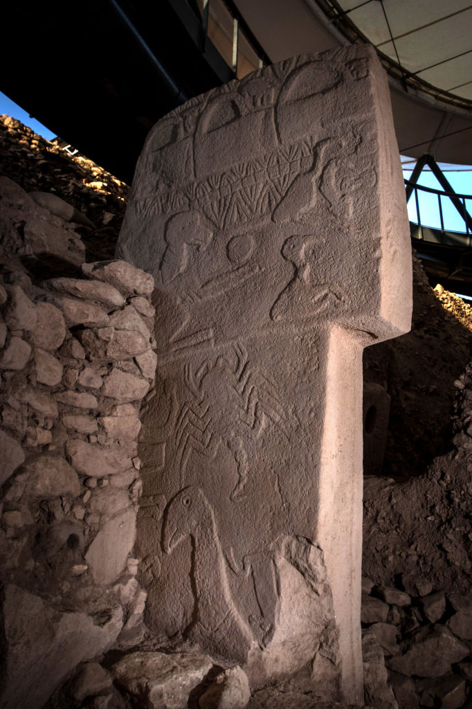 a t-shaped pillar with a series of bird figurines and v-shaped carvings