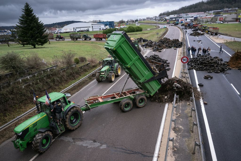 A farmer pulls waste to block the RN 19 near in Vesoul, eastern France, on January 25, 2024. French farmers continued their actions on January 25, 2024, and are eagerly awaiting a response from the government to their request for &quot;immediate&quot; aid worth several hundred million euros. (Photo by SEBASTIEN BOZON / AFP)