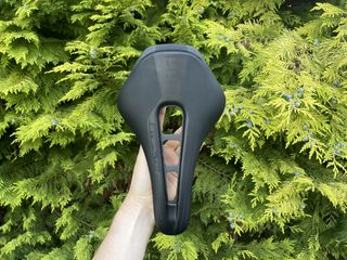 PRO Stealth Superlight saddle held up in front of a conifer tree
