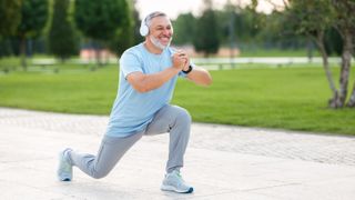 a man in headphones doing a lunge outside