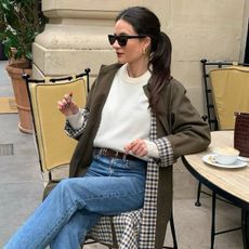 woman in white sweater, jeans, and trench coat