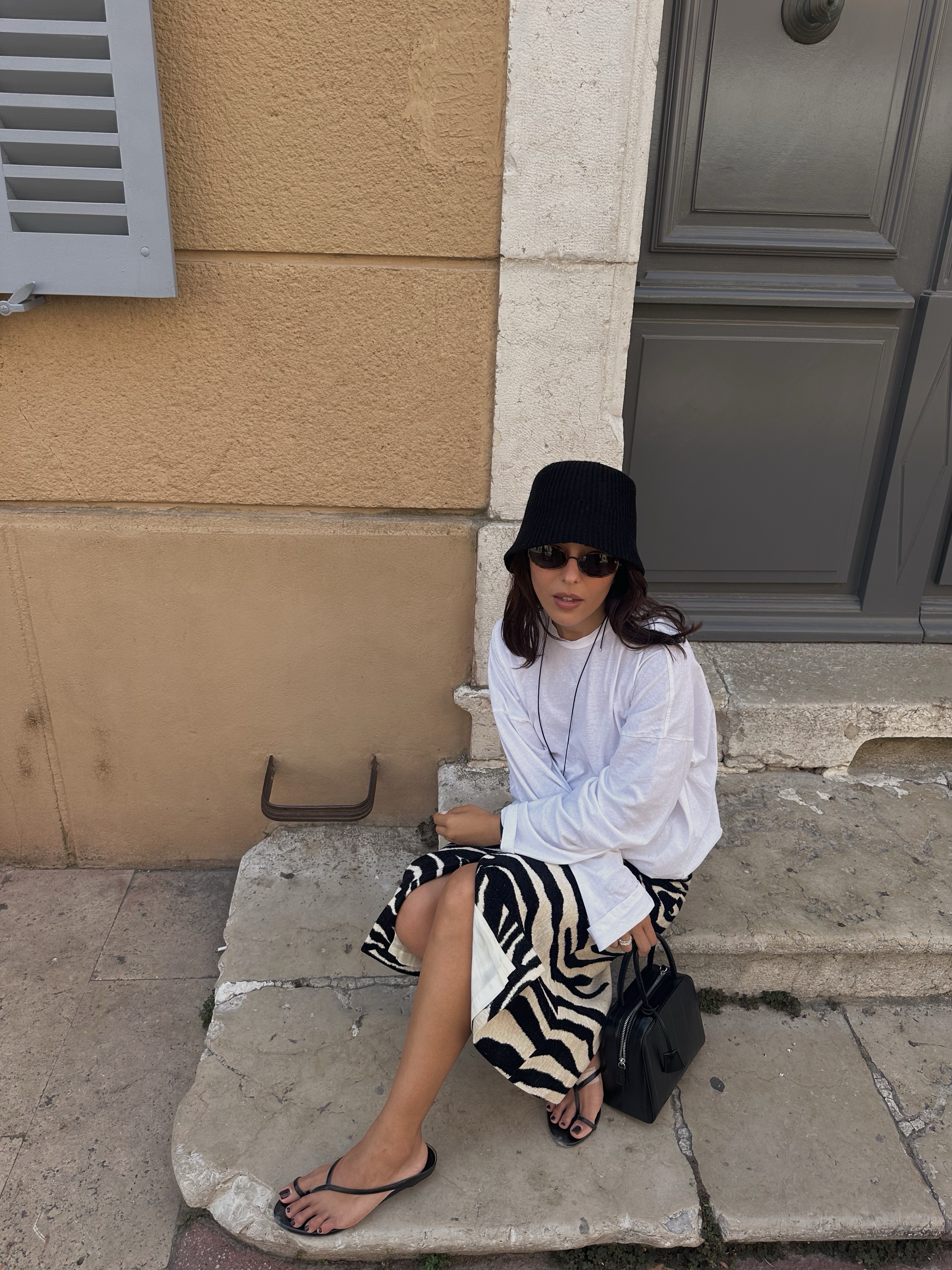 Woman in a long sleeve white tee and printed skirt.
