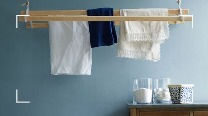 Blue laundry room with a pulley drying rack with white and blue items hanging to dry with a counter of laundry products below