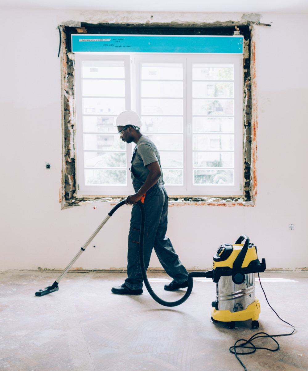 A man vacuuming a sanded parquet floor using an industrial vacuum