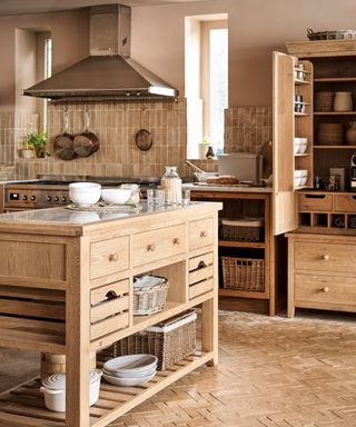 A large solid wood standalone kitchen islandi n the center of a matching rustic kitchen