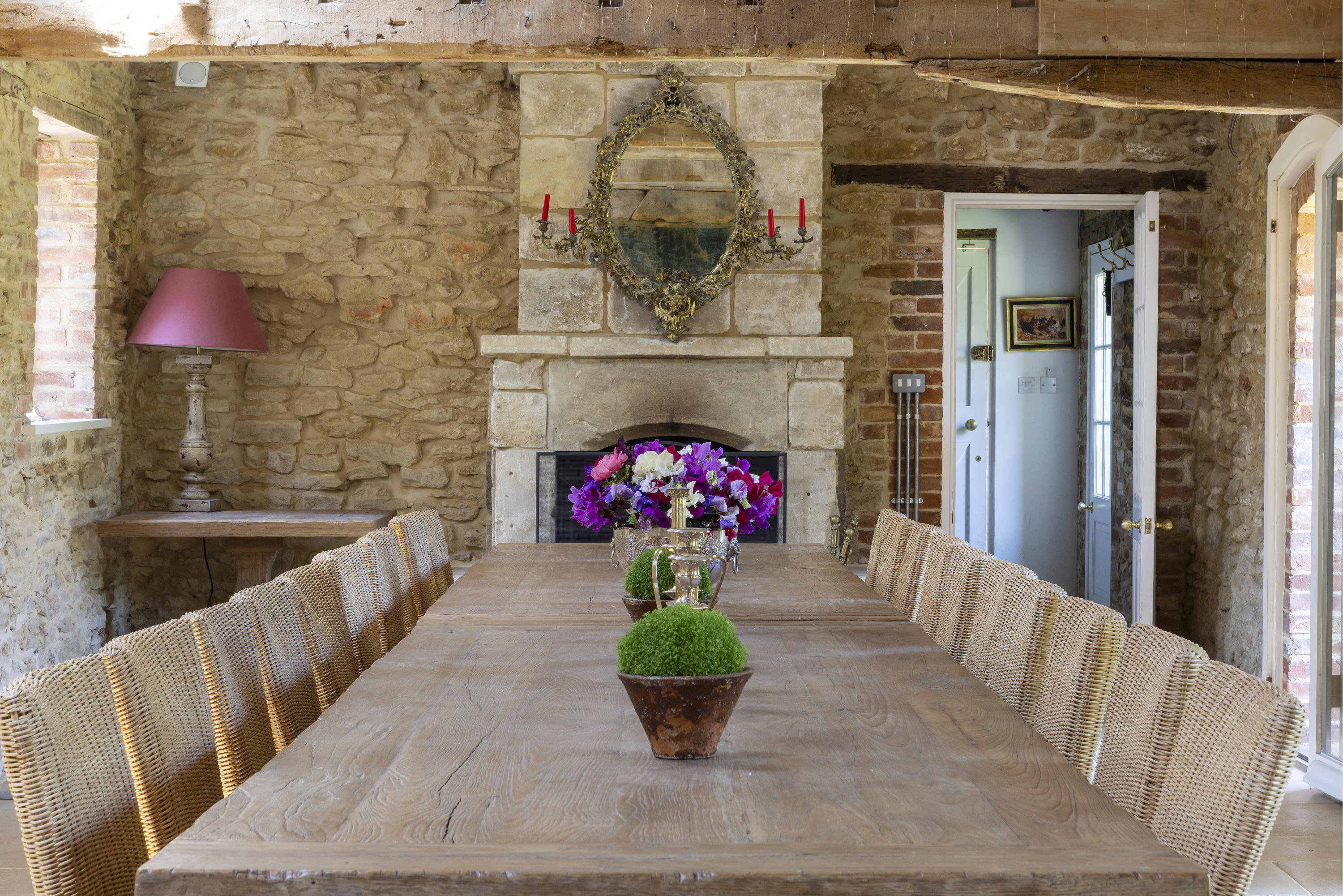 Inside Mount Farm's dining room. A wooden table with many chairs and a flower arrangement in its centre