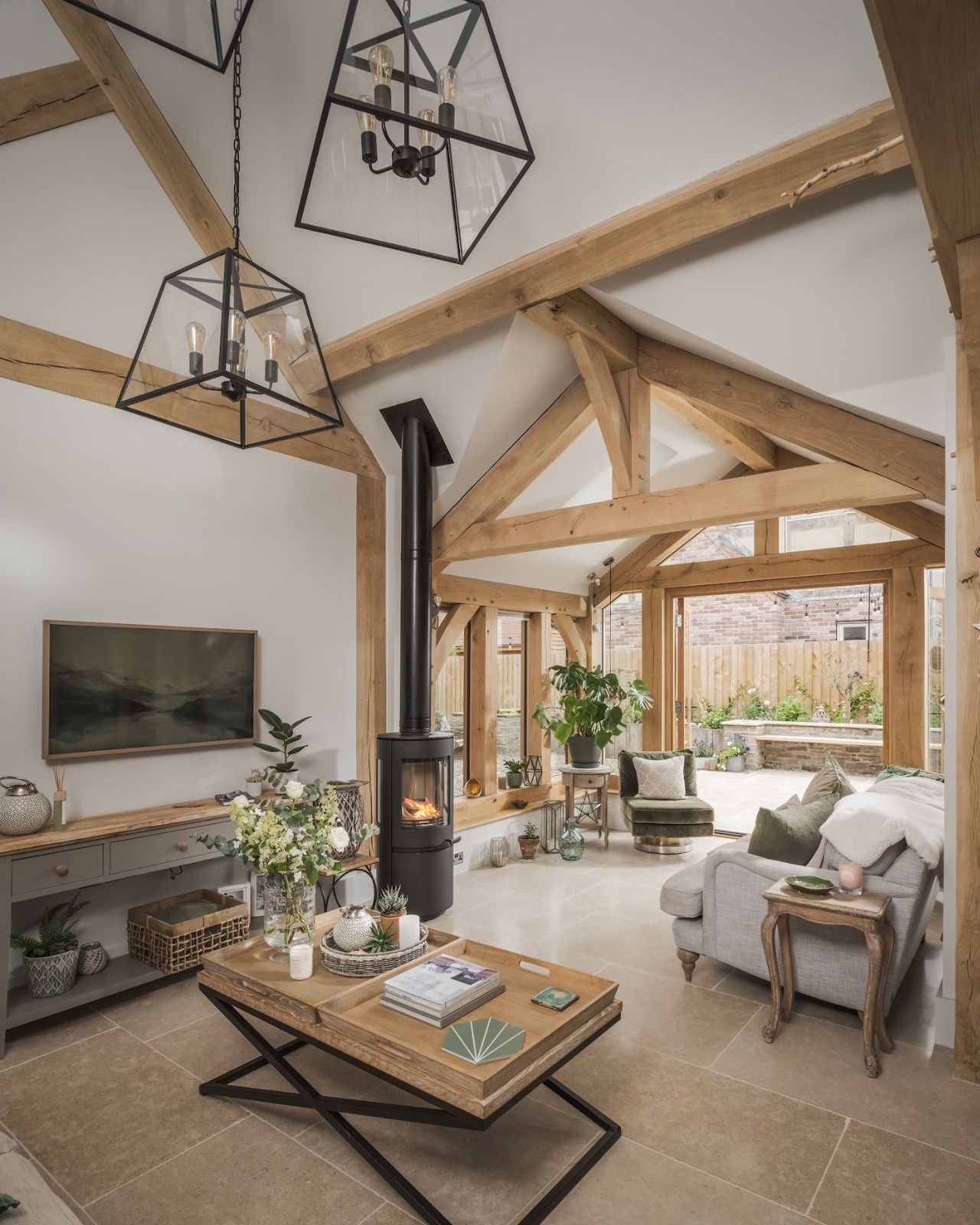 The interior of an oak frame home with exposed wooden beams and a log burner