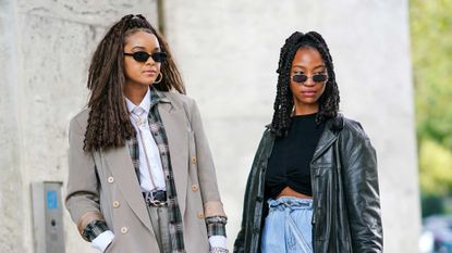 Two young women in 2000s fashion or y2k trends, like plaid, leather and rectangular sunglesses, are pictured during paris fashion week