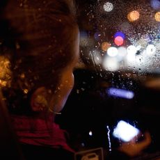 View of woman through car window, raining at night