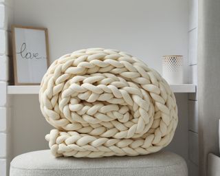 Cream colored chunky knit blanket rolled up