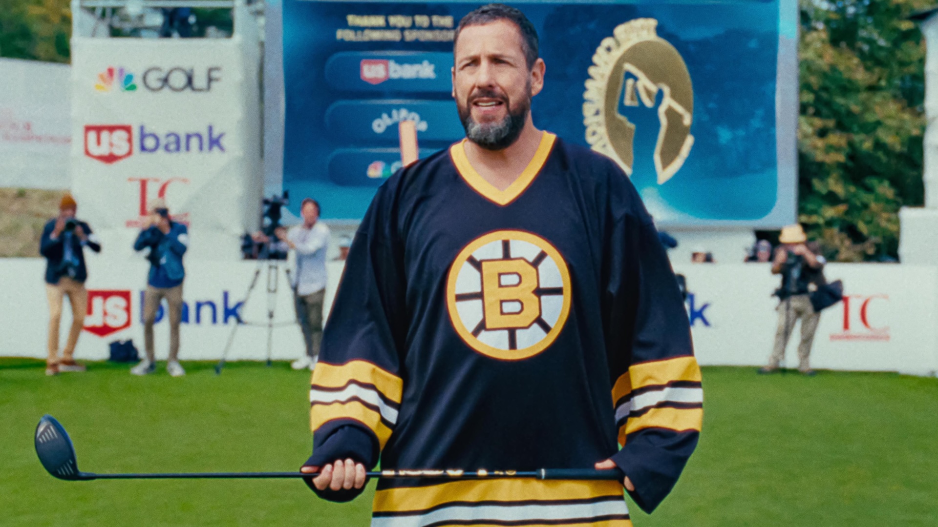 Adam Sandler holding a golf club whilst staring into the distance 