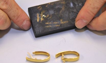 A pawn shop employee tests the karat amount in a pair of gold earrings. 