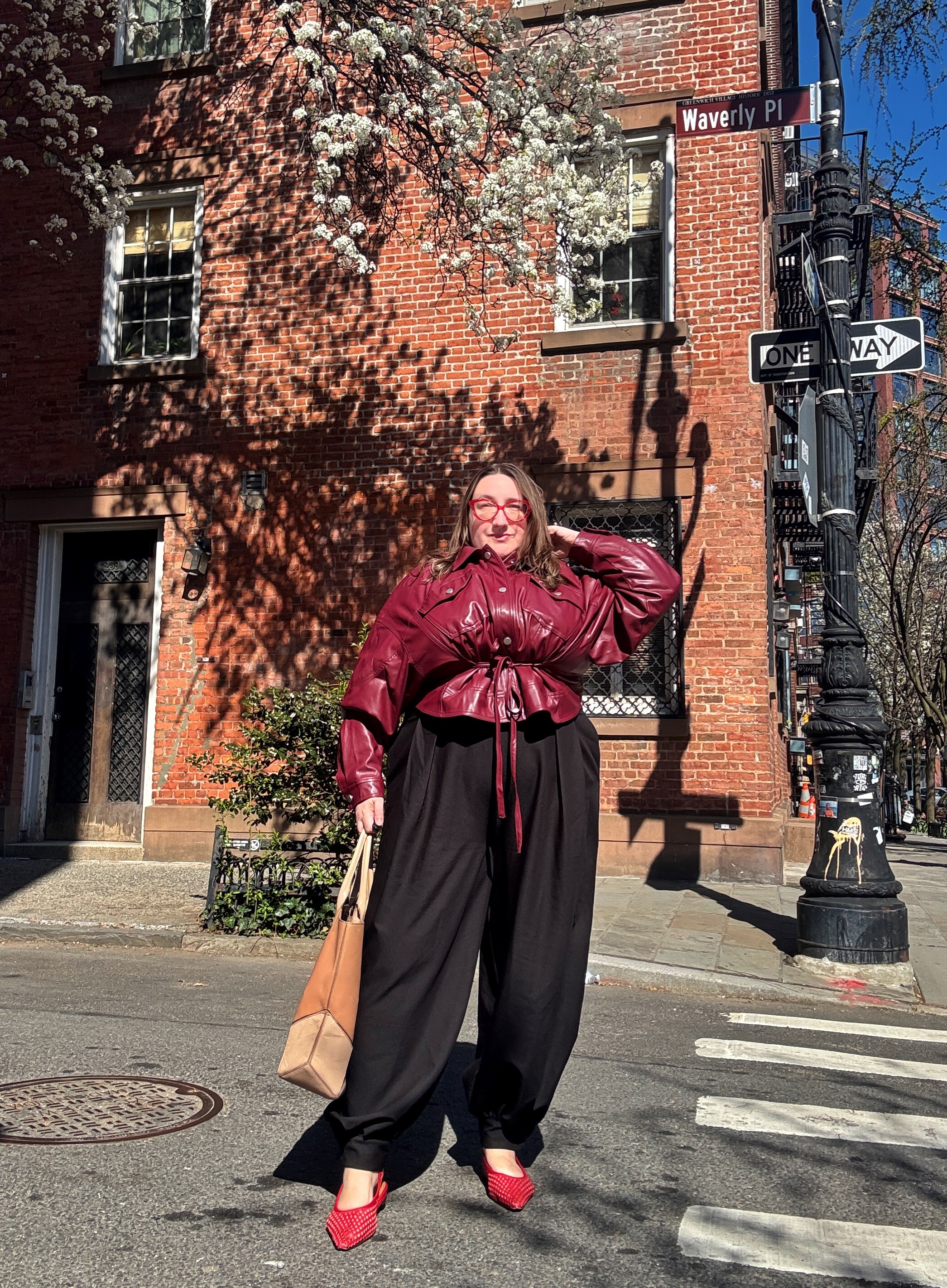Sarah Chiwaya poses in red Andr&amp;eacute; Assous mules with a cinched bomber and balloon pants