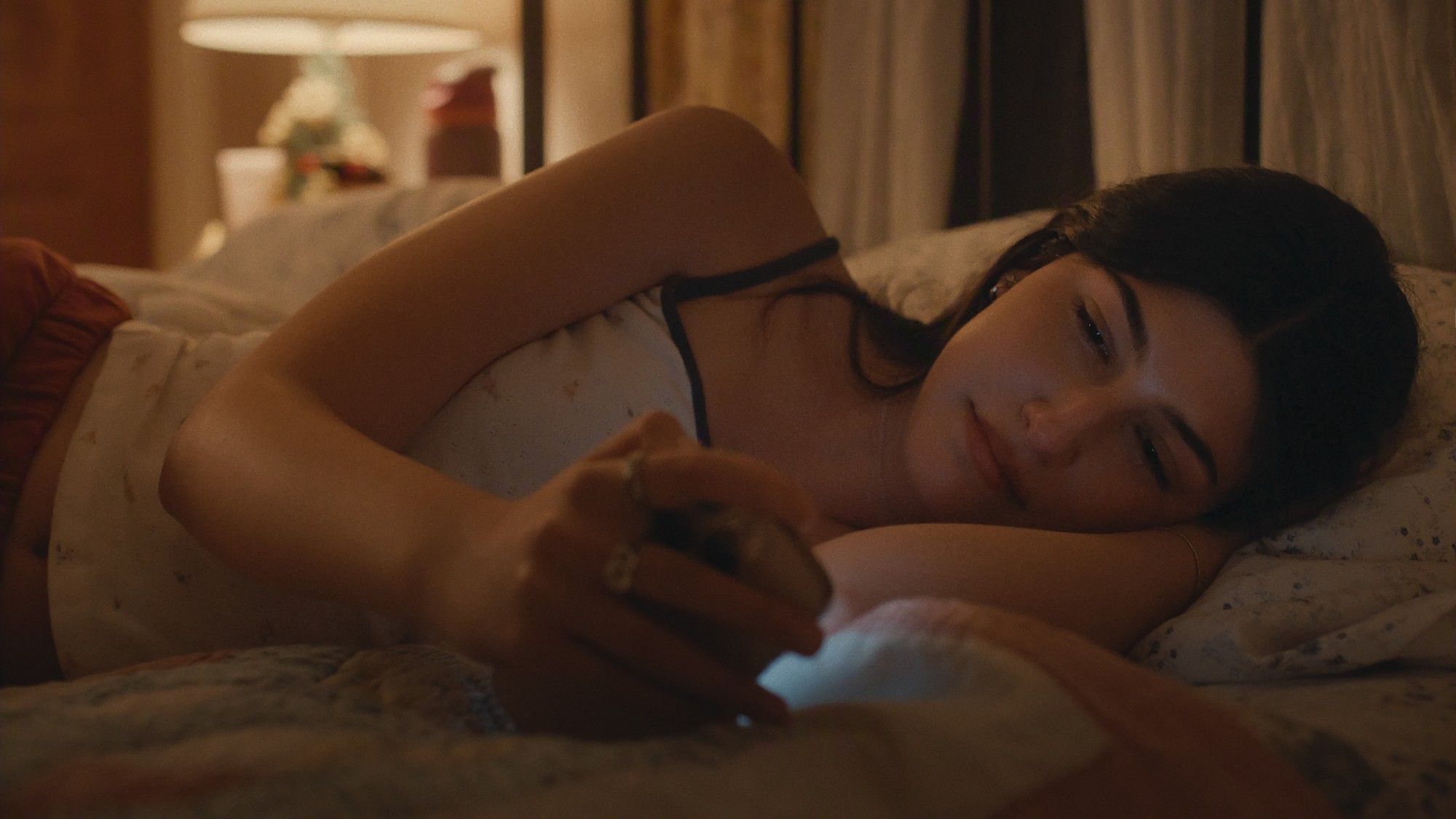 Sophie laying in bed looking at her phone.