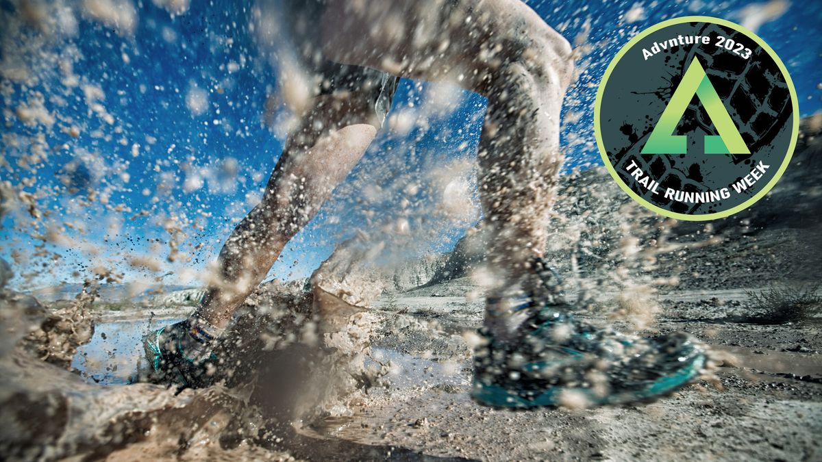 Close-up of trail runner&#039;s shoes as he runs through puddle