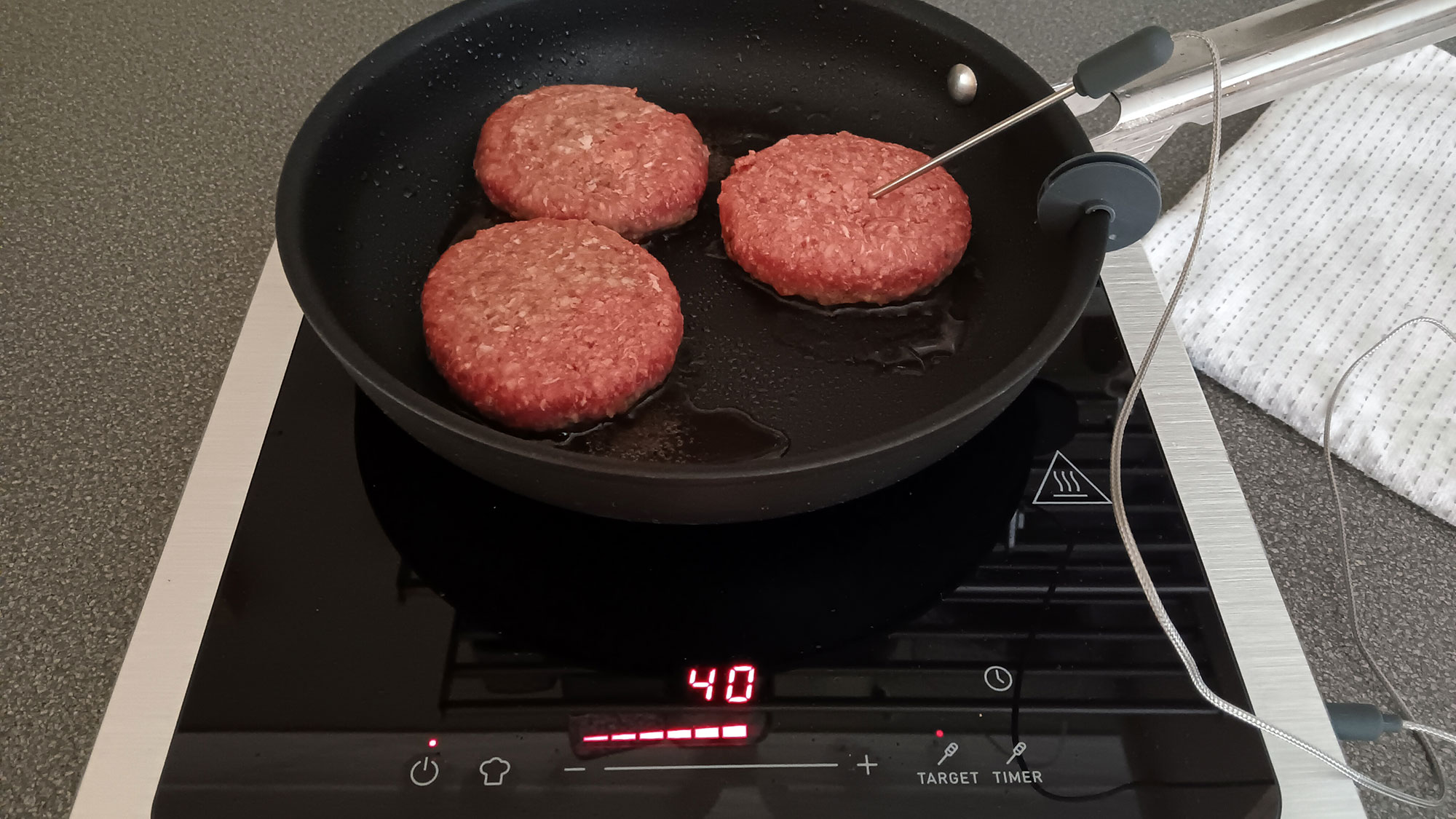 Burgers frying on Smeg portable induction cooktop