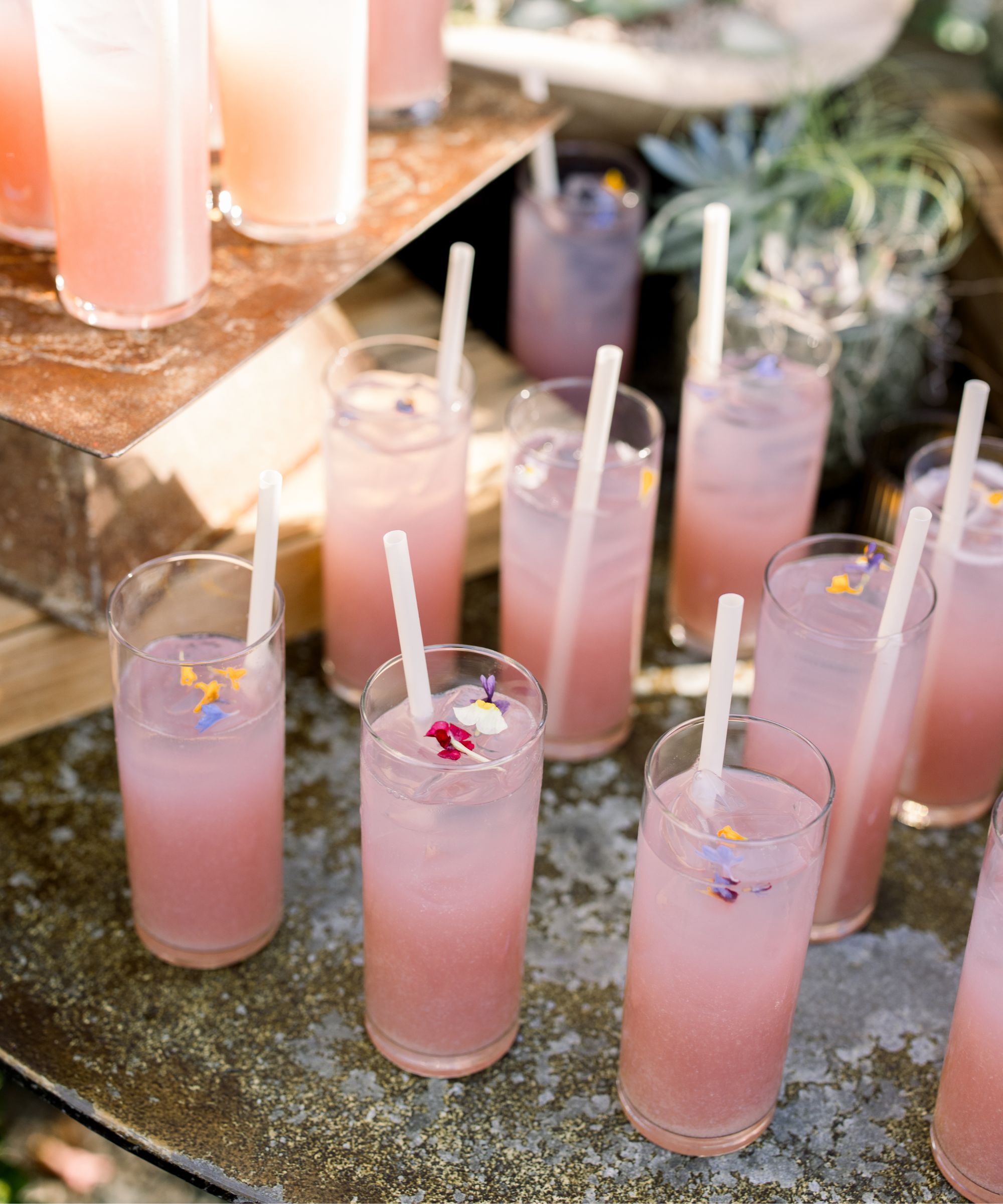 Glasses of pink drinks with edible flowers and straws