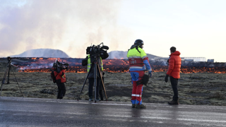 Emergency personnel pictured on road as lava flows in the background