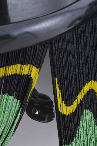 A black snake head peeking out of a beaded curtain