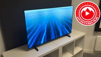 A 42-inch LG C6 OLED TV on a white set of shelves, with a logo next to it that reads "Adventures in AV2